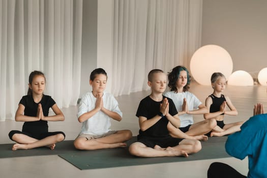 Children sit on mats in the lotus position in Yoga classes. Children's yoga.