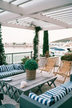 Lounge area of an open-air restaurant by the sea with sofas, armchairs and a table. High quality photo