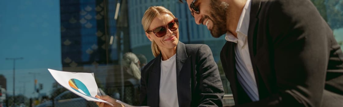 Business colleagues working with documents sitting outside of office on cafe terrace