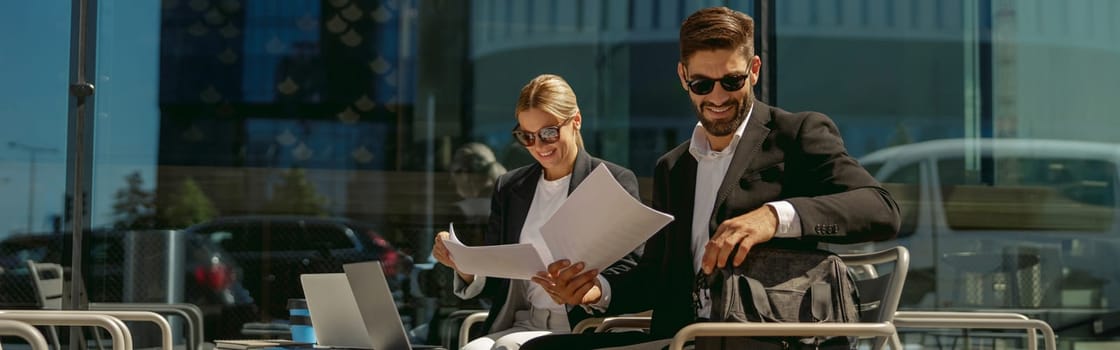 Two business partners working with documents sitting outside of office on cafe terrace