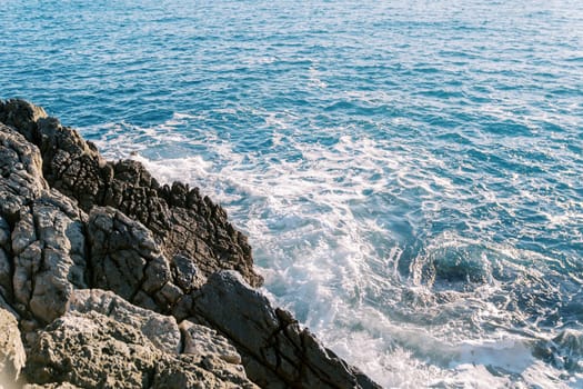 Blue sea foams hitting the rocky high shore. High quality photo