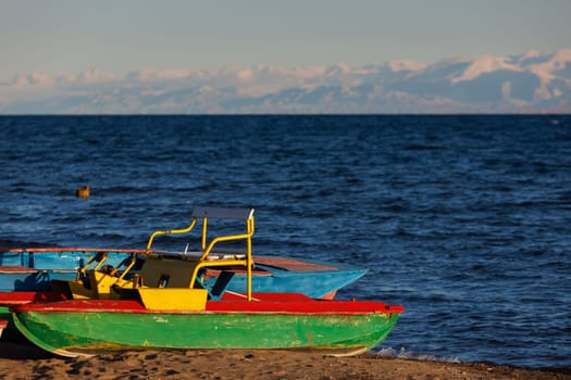 old pedal catamarans on beach of mountain lake at sunny autumnal afternoon.