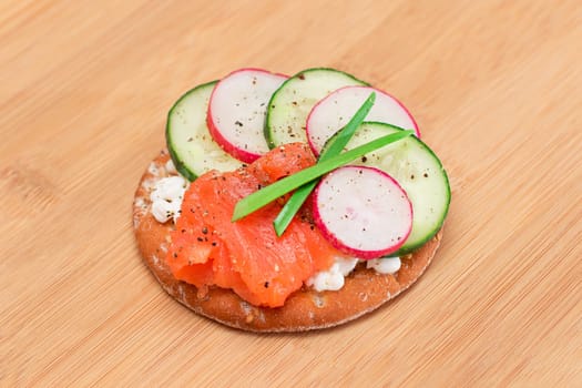 Crispy Cracker Sandwich with Salmon, Cucumber, Radish, Cottage Cheese and Green Onions on Bamboo Cutting Board. Easy Breakfast. Quick and Healthy Sandwiches. Crispbread with Tasty Filling