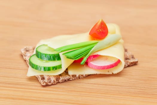 Whole Grain Crispbread with Cheese, Fresh Cucumber, Radish, Tomato and Green Onions on Cutting Board. Quick and Healthy Sandwiches. Crispbread with Tasty Filling. Healthy Dietary Snack