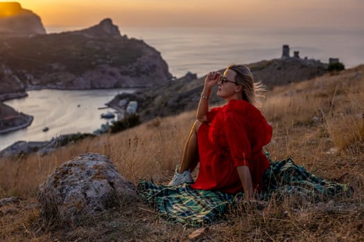 Woman sunset sea mountains. Happy woman siting with her back on the sunset in nature summer posing with mountains on sunset, silhouette. Woman in the mountains red dress, eco friendly, summer landscape active rest.