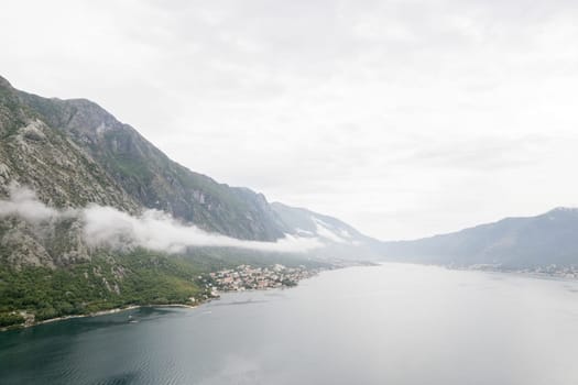 Fog descends in waves from the mountain ridge to the Bay of Kotor. Montenegro. Drone. High quality photo
