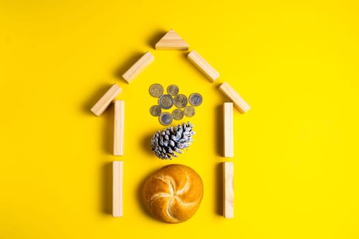 Hand holding money coins close to bread on a yellow background