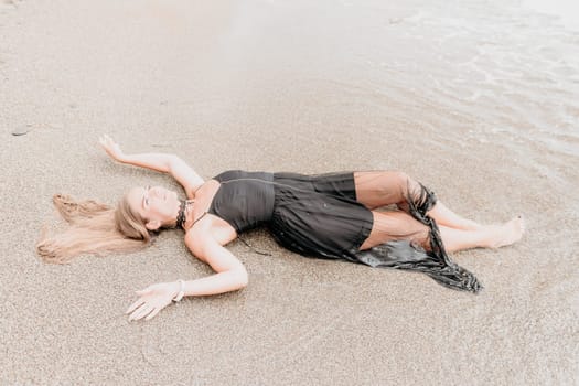 Woman travel sea. Young Happy woman in a long red dress posing on a beach near the sea on background of volcanic rocks, like in Iceland, sharing travel adventure journey