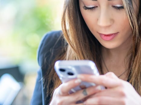 mixed asian race woman using cellphone, chatting on internet, working or studying online, making a selfiee outdoors