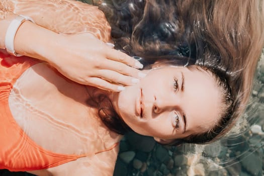 Side view a Young beautiful sensual woman in a mint long dress posing on a volcanic rock high above the sea during sunset. Girl on the nature on overcast sky background. Fashion photo