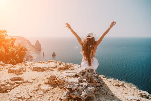 Woman travel sea. Young Happy woman in a long red dress posing on a beach near the sea on background of volcanic rocks, like in Iceland, sharing travel adventure journey