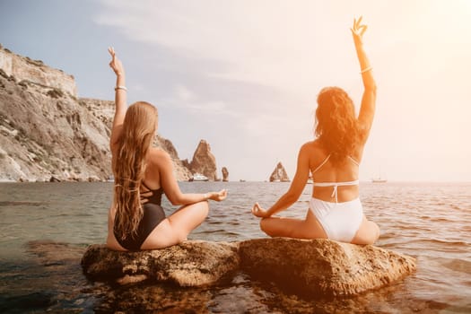 Woman sea yoga. Back view of free calm happy satisfied woman with long hair standing on top rock with yoga position against of sky by the sea. Healthy lifestyle outdoors in nature, fitness concept.