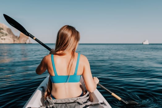 Woman in kayak back view. Happy young woman with long hair floating in transparent kayak on the crystal clear sea. Summer holiday vacation and cheerful female people relaxing having fun on the boat