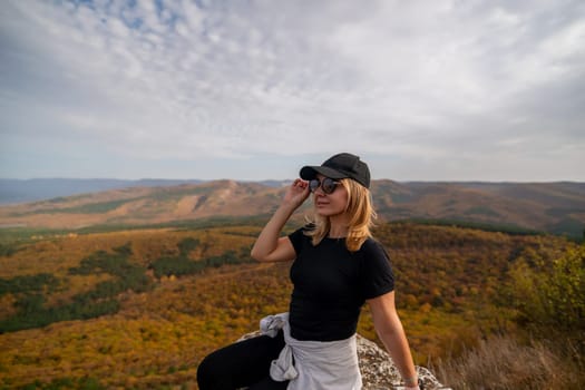 woman on mountain peak looking in beautiful mountain valley in autumn. Landscape with sporty young woman, blu sky in fall. Hiking. Nature.