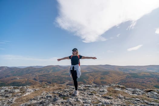 woman backpack on mountain peak looking in beautiful mountain valley in autumn. Landscape with sporty young woman, blu sky in fall. Hiking. Nature.