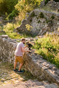 Cameraman in summer outfit with gimbal and cinema camera in his hands making travel video with old europe Balkan nature on the background.