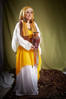 A girl or young woman from ancient Israel, Palestine, Iran, Iraq with a clay jug. A biblical story with Rebekah and water. Stylized photo shoot with a model in Middle Eastern clothes