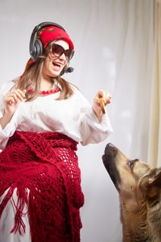 Young girl in red scarf, large headphones with microphone and black glasses and big shepherd dog. Woman who is radio or television presenter, female telecom operator, blogger or Freelancer and animal