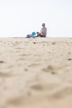 Mother playing his infant baby boy son on sandy beach enjoying summer vacationson on Lanzarote island, Spain. Family travel and vacations concept. Copy space.