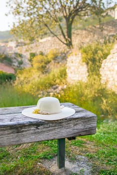 Summer nature background. Braided straw hat on bench in garden. spring season. Rustic composition nature. Relax voyage time. Copy space and mock up place for text.