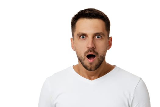 Portrait of young surprised handsome bearded man with shocked facial expression on white background