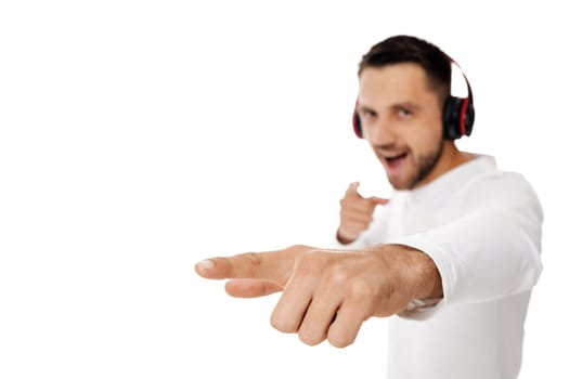 handsome smiling young man in headphones listening to music and points hand at you, isolated on white background. focus on hand