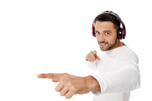 handsome young man in headphones listening to music and points hand at you, isolated on white background.