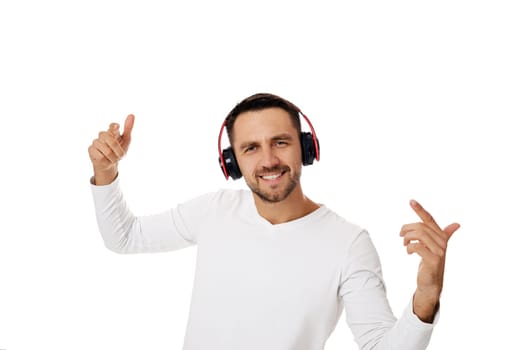 happy handsome young bearded man in headphones listening to music and dancing isolated on white background.