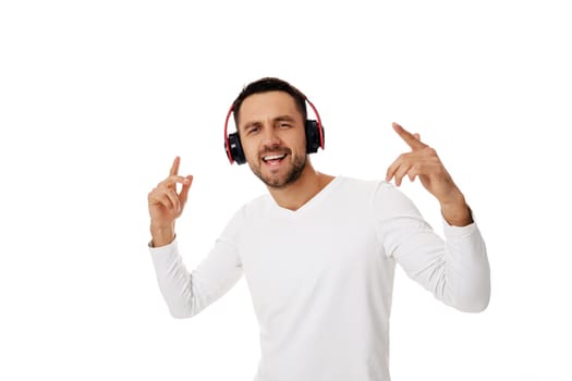 handsome young man in headphones listening to music and dancing isolated on white background.