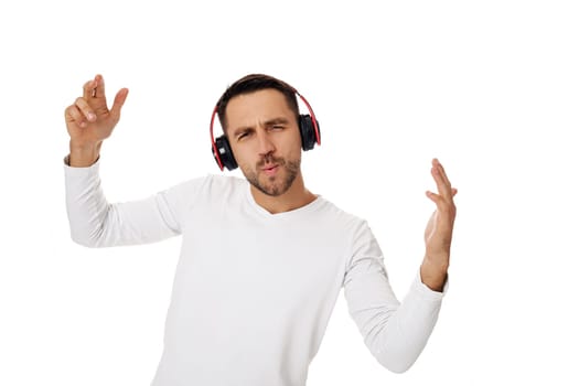 handsome young bearded man in headphones listening to music and dancing isolated on white background.