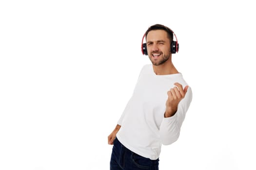 handsome young man in headphones listening to music and dancing isolated on white background.