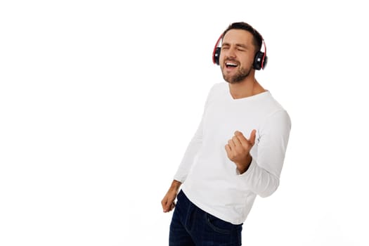 handsome young man in headphones listening to music and playing an imaginary guitar isolated on white background.