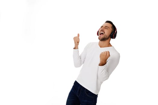 handsome young man in headphones listening to music and dancing isolated on white background.