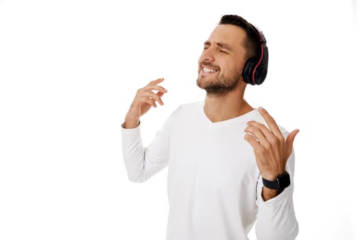 handsome smiling young bearded man in headphones listening to music, dancing and singing isolated on white background.