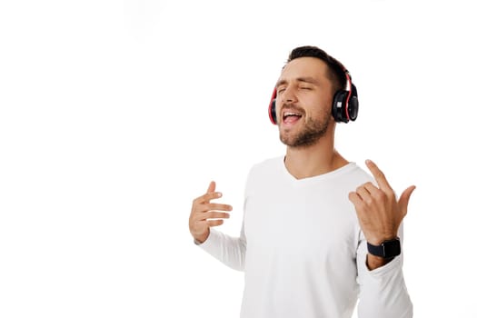 handsome young man in headphones listening to music and dancing isolated on white background.