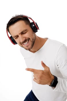 handsome smiling young man in headphones listening to music, dancing and singing isolated on white background.