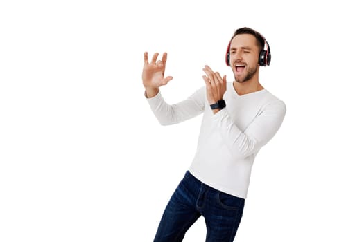 handsome young man in headphones listening to music and playing an imaginary musical trumpet isolated on white background.