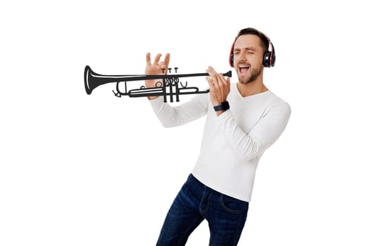 handsome young man in headphones listening to music and playing an imaginary musical trumpet isolated on white background.