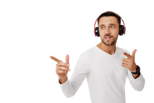 handsome young man in headphones listening to music and dancing isolated on white background.