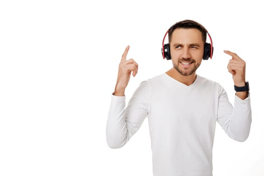 handsome smiling young man in headphones listening to music, dancing and singing isolated on white background.