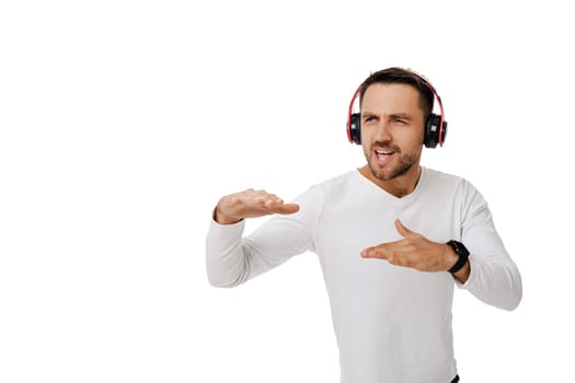 handsome young bearded man in headphones listening to music and dancing isolated on white background.