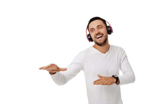 handsome smiling bearded young man in headphones listening to music, dancing and singing isolated on white background.