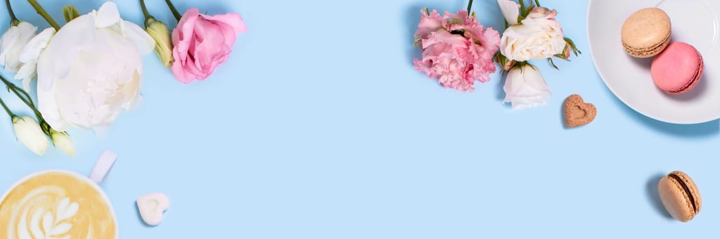Blue background with flowers, macaroons, and a Cup of coffee. Top view with space for your text.