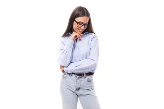young pretty european brunette business woman with light makeup in a light blue blouse wears glasses for an image to work on a white background with copy space.
