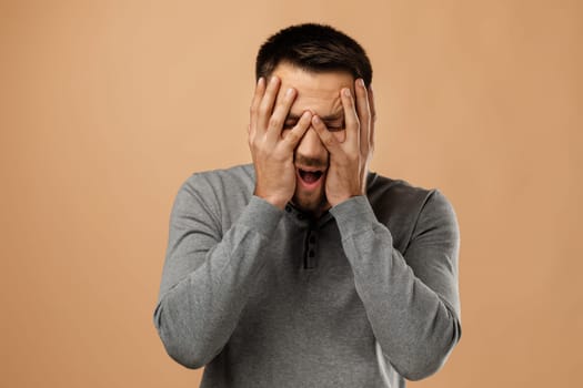 upset bearded man keeps hand on head isolated on beige background. man regrets or forget about something