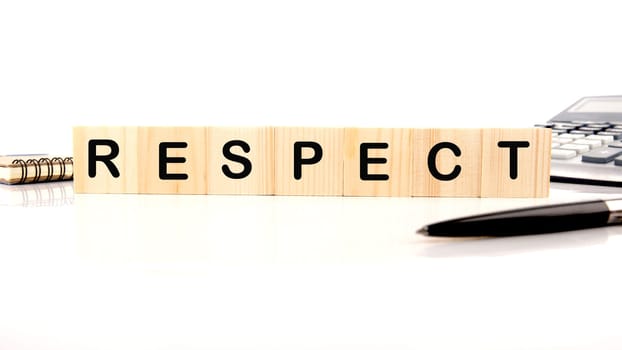 respect word assembled from wooden cubes next to a calculator, pen and notepad