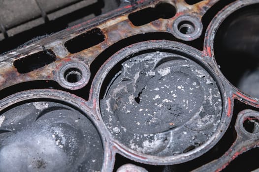 Close-up of a damaged piston of an internal combustion engine with carbon deposits in the cylinder block of a faulty engine. Pieces of metal broken off from the piston