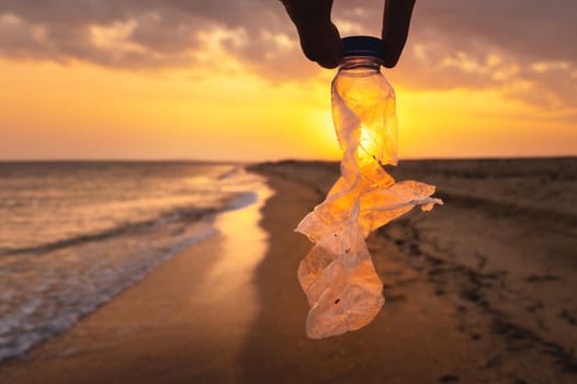 Volunteer woman collecting plastic holey bottle for beach cleanup, women cleaning up trash, ecology concept and World Environment Day, saving the Earth concept.