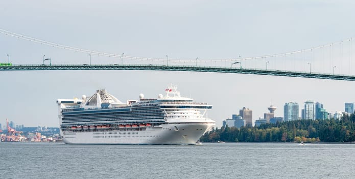 Huge white ocean cruise liner passing famous Lion Gates Bridge in Vancouver, Canada