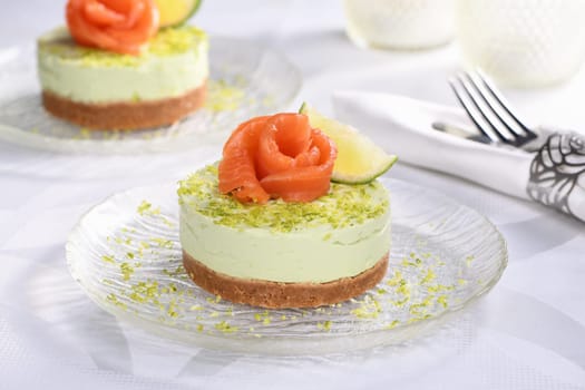 Timbale appetizer made from avocado, whipped with soft cheese cream and lime on short crust pastry with salmon. A great option for a holiday menu.